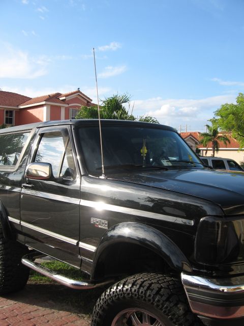 1994 Ford Bronco - A black Ford Bronco is parked outside a house, with an antenna on its roof.