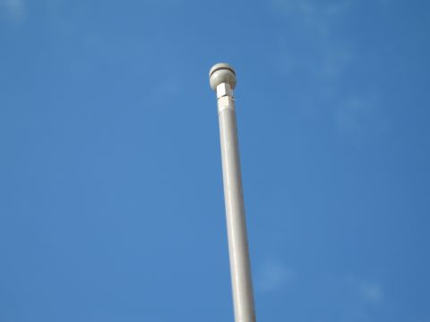 1994 Ford Bronco - A flagpole extends upwards against a clear blue sky, with a website logo visible at the base.
