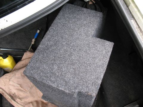 1997 Ford Crown Victoria - A gray subwoofer box is visible in the trunk of a car, alongside a yellow container and some tools.