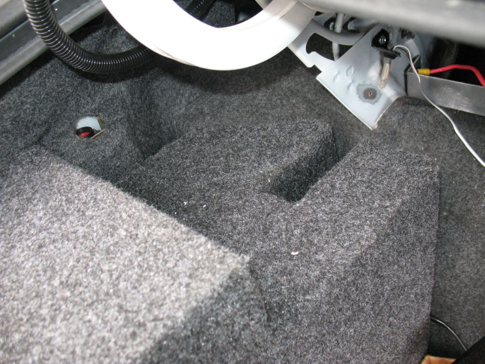Car trunk carpet with some wiring and brackets visible