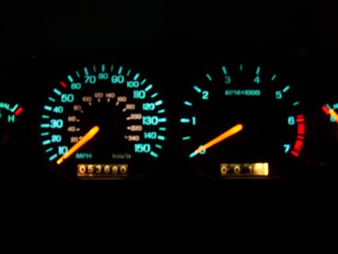 1996 Mercury Grand Marquis - The illuminated instrument cluster shows a speedometer and tachometer with glowing orange needles against a dark background.