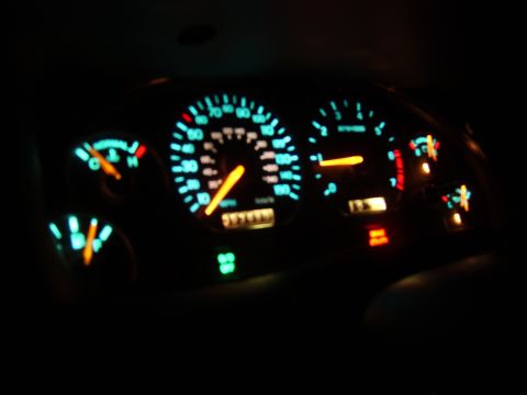 1996 Mercury Grand Marquis - The illuminated dashboard gauges display speed, RPM, fuel level, and temperature, with warning lights illuminated.