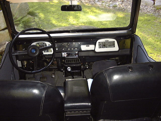 1974 Toyota Land Cruiser FJ40 interior dashboard, steering wheel, and seats. Land Cruiser badge visible
