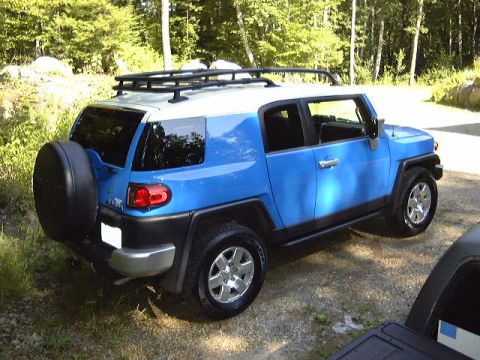 2007 Toyota Land Cruiser - A blue Toyota FJ Cruiser is parked on a gravel surface with trees in the background.