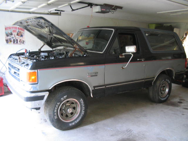 Two-tone gray and black Ford Bronco with hood open, showing engine