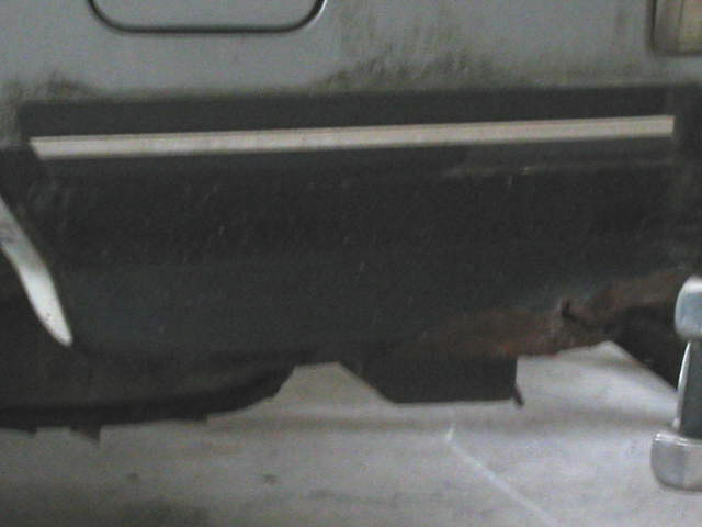 Close-up of rusty rocker panel and frame on a vehicle