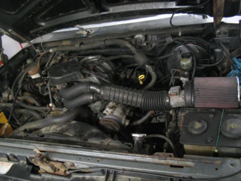 1989 Ford Bronco - The engine bay of a vehicle, an aftermarket air filter and numerous hoses and components.