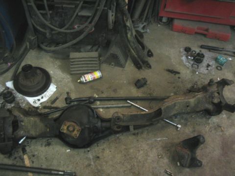 1989 Ford Bronco - Front axle assembly and associated parts laid out on a garage floor.