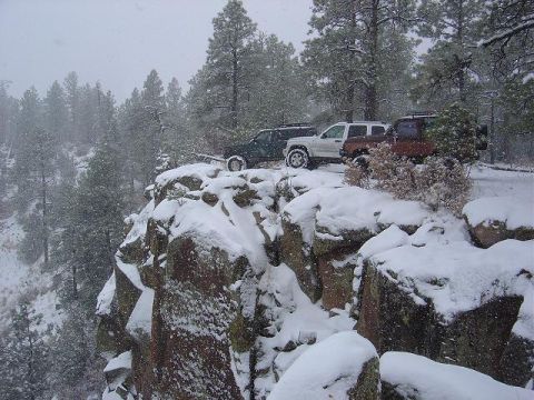 1956 Ford Bronco II - Four-wheel drive vehicles are parked on a rocky, snow-covered ledge during a winter storm.