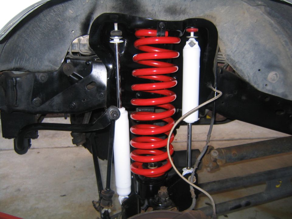 Front coil spring suspension with red coil and white shocks