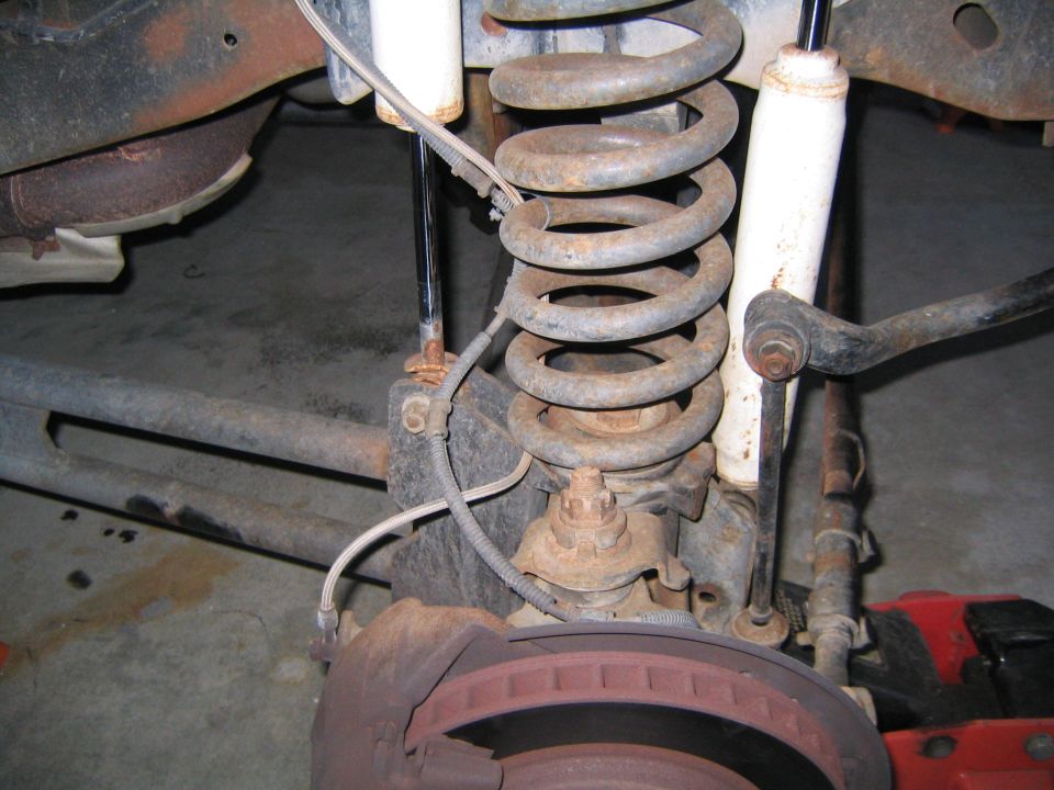 Rusty coil spring suspension and brake rotor under a vehicle