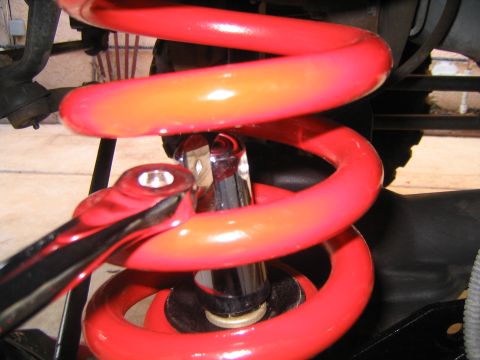 1993 Ford Bronco - Close-up of a red coil spring and shock absorber assembly, with a wrench on the spring.