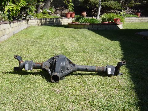 1983 Ferrari Enzo - A rear axle differential assembly rests on a grassy lawn, with a brick wall and garden in the background.