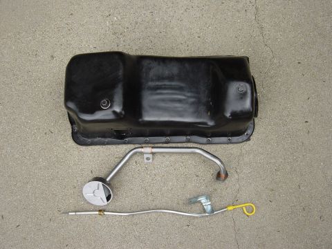1983 Ferrari Enzo - A black oil pan and a metal dipstick with a yellow handle are laid out on a concrete surface.