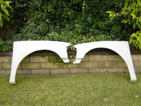 1983 Ferrari Enzo - Pair of white car fenders displayed outdoors on grass and against a brick wall.