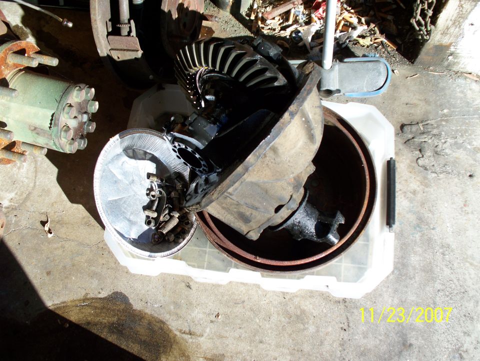 Differential housing and brake parts in a plastic tub, with a green hydraulic component nearby