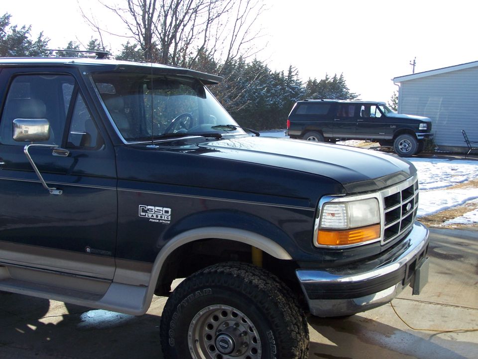 Dark blue Ford F-Series truck, front quarter view. Another dark SUV is parked behind it