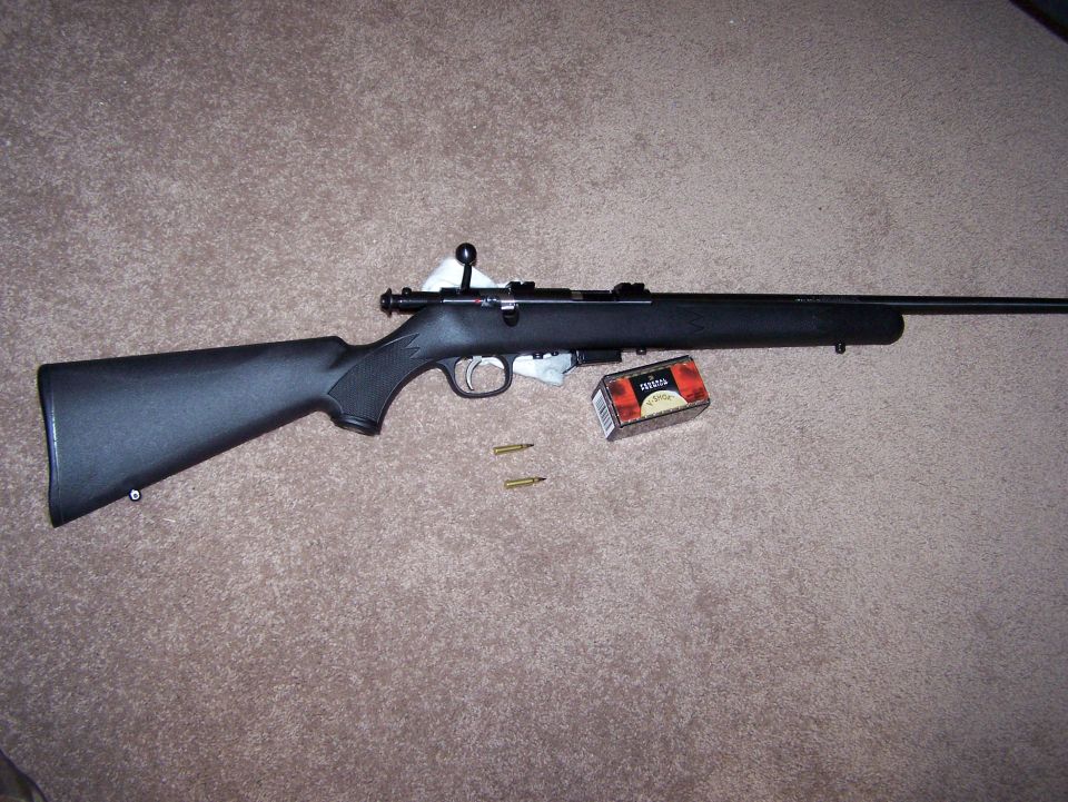 Black rifle with box of ammunition and two loose cartridges