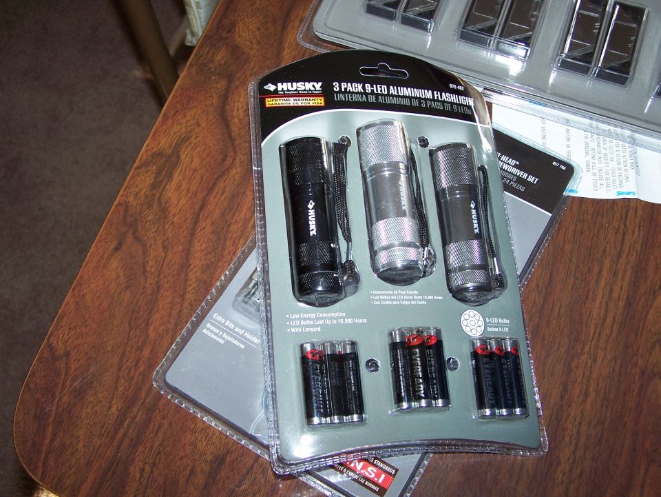 Husky 3-pack aluminum flashlights with batteries on a wooden table