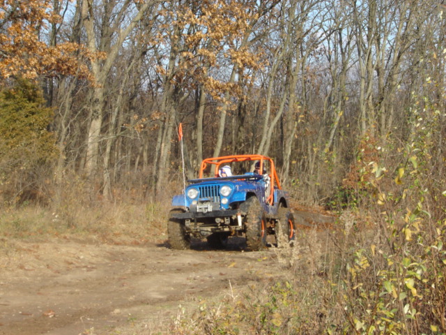 Blue Jeep with orange roll cage off-roading on a dirt path