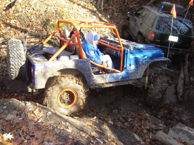 Blue Jeep with orange roll cage going off-road, another SUV behind it