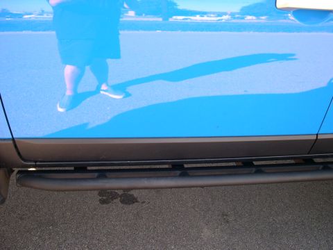 2007 Toyota FJ Cruiser - A blue 2007 Toyota FJ Cruiser's side door and step are shown, with a reflection of a person in the paint.