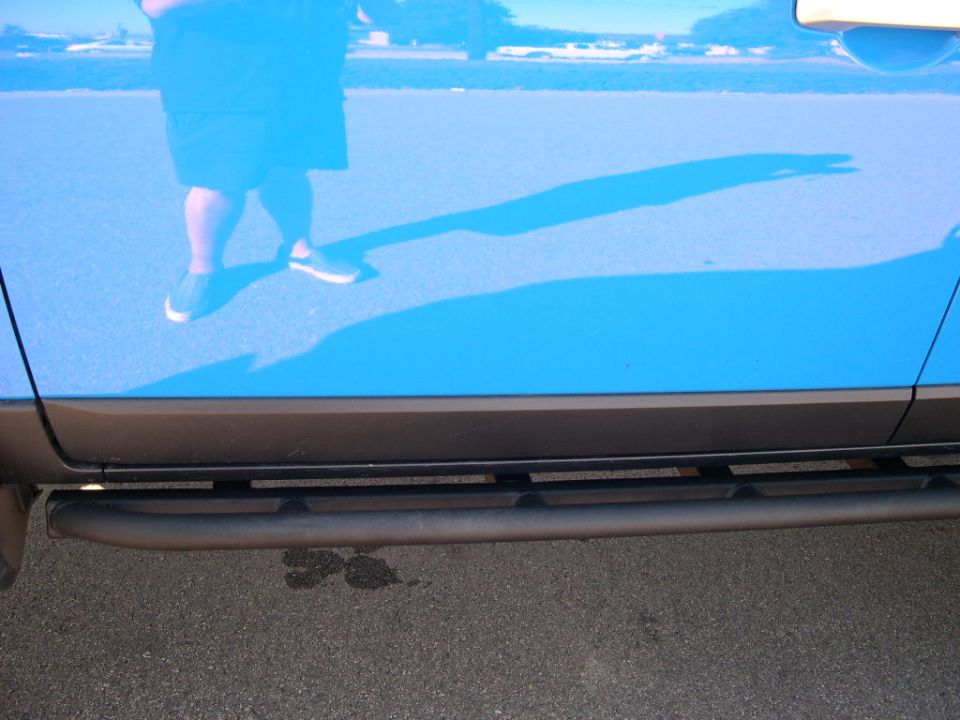 Blue 2007 Toyota FJ Cruiser side door with black tubular step and reflection of person