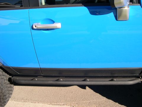 2007 Toyota FJ Cruiser - Close-up of the side of a blue Toyota FJ Cruiser, highlighting the door and aftermarket step rails.