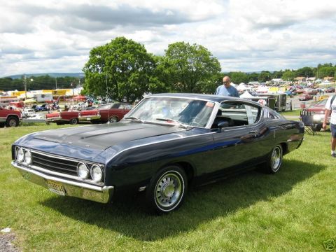 1969 Ford Torino - A dark blue 1968 Ford Torino coupe is displayed on a grassy field with other vehicles and tents in the background.