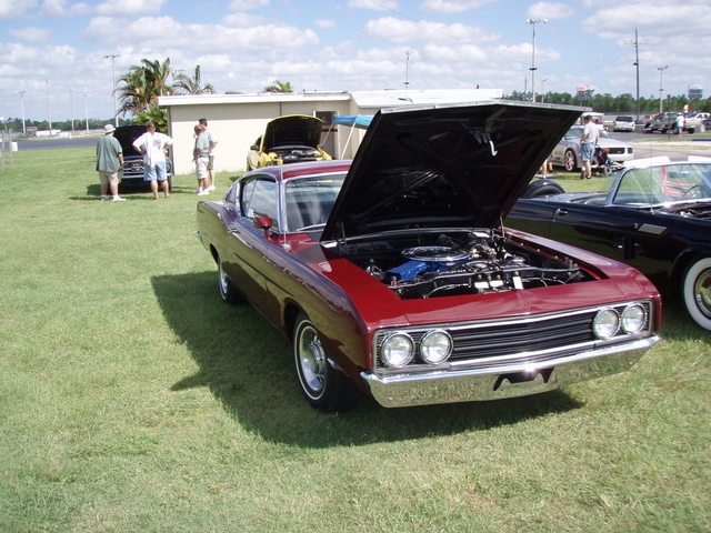 1969 Ford Torino with hood open, parked on grass next to other cars