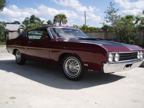 1969 Ford Torino - A maroon 1969 Ford Torino coupe is parked outdoors, showing its distinctive grille and hood scoop.