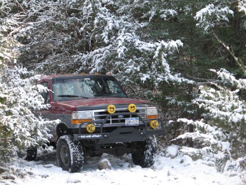 1995 Ford Bronco - 1995 Ford Bronco navigating snowy terrain with auxiliary lights and off-road bumper.