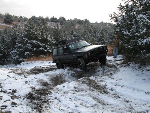 1995 Ford Bronco - Jeep Cherokee XJ navigating a challenging snowy and muddy path during winter.