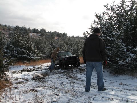 1995 Ford Bronco - A Jeep Cherokee is stuck in the snow as two people attempt to free it.