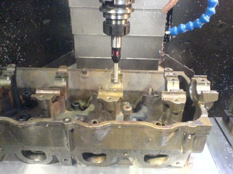 1964 Ford 427 - A cylinder head is being machined on a CNC mill with a probe touching the surface.