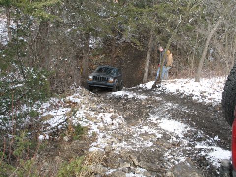1995 Ford Bronco - A black Jeep Cherokee XJ is seen on a challenging, snow-dusted trail with two observers present.