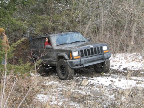 1995 Ford Bronco - Jeep Cherokee XJ navigating difficult terrain with a tow strap attached.