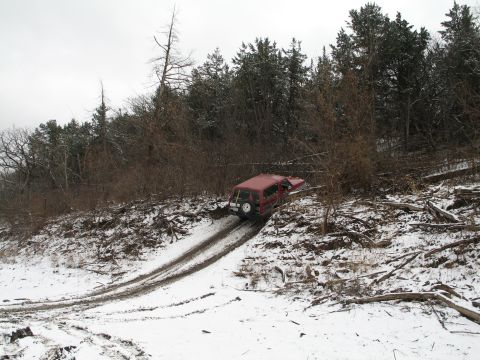 1995 Ford Bronco - Red SUV navigating a snowy, wooded incline.
