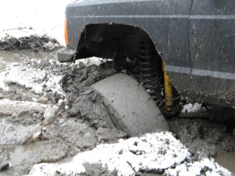 1995 Ford Bronco - This vehicle is stuck in a muddy and snowy terrain, with one tire completely submerged.