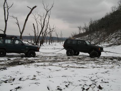 1995 Ford Bronco - Two Jeep Cherokees are winched out of a snowy, barren landscape with dead trees.