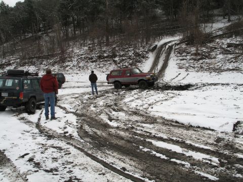 1995 Ford Bronco - Two SUVs navigate a challenging snowy and muddy off-road course.