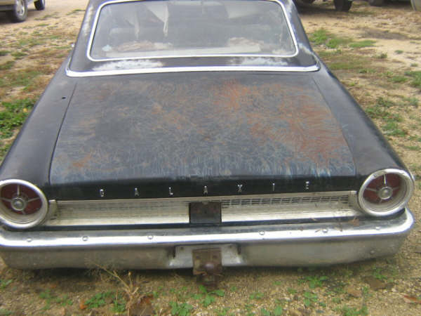 1963 Ford Galaxie rear view, black paint with rust spots, chrome bumper, round taillights