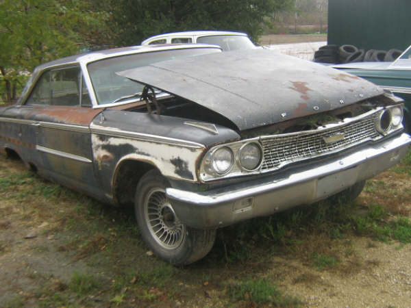 Weathered Ford fastback project car with hood open, front three-quarter view