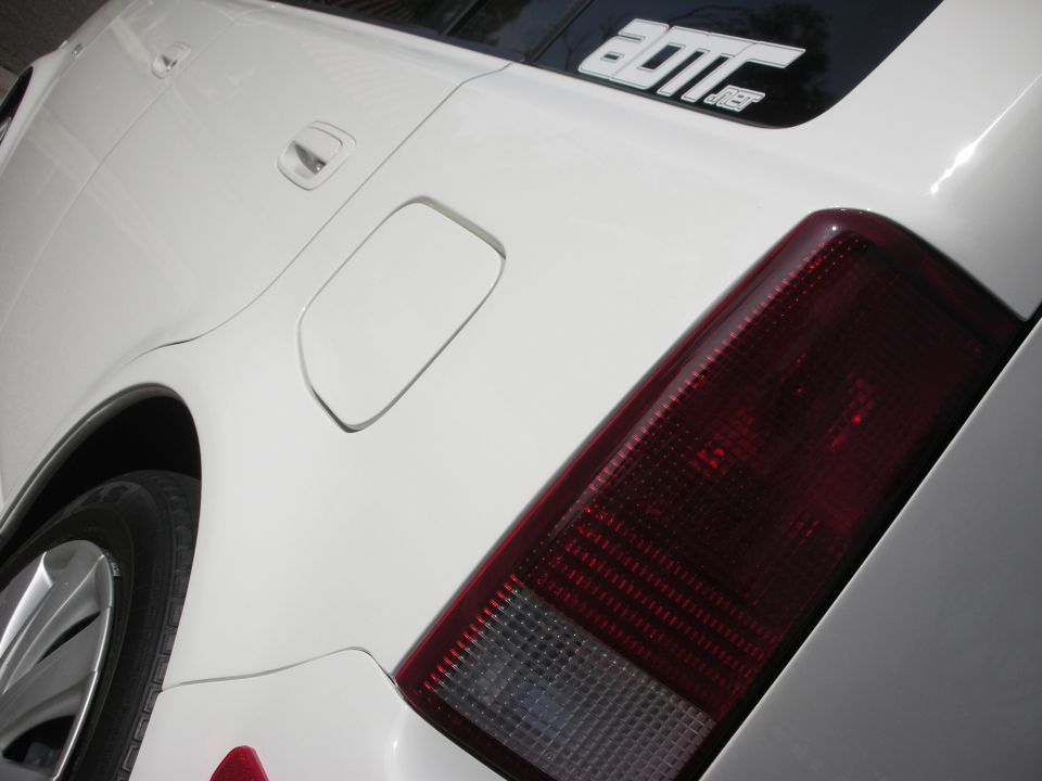 White sedan rear fender fuel door and red taillight close-up with alloy wheel