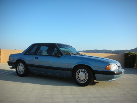 1990 Ford Mustang - Side view of a blue 1990 Ford Mustang coupe with a 5.0 badge visible.