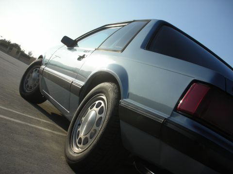 1990 Ford Mustang - Rear quarter view of a light blue 1990 Ford Mustang coupe under a clear sky.