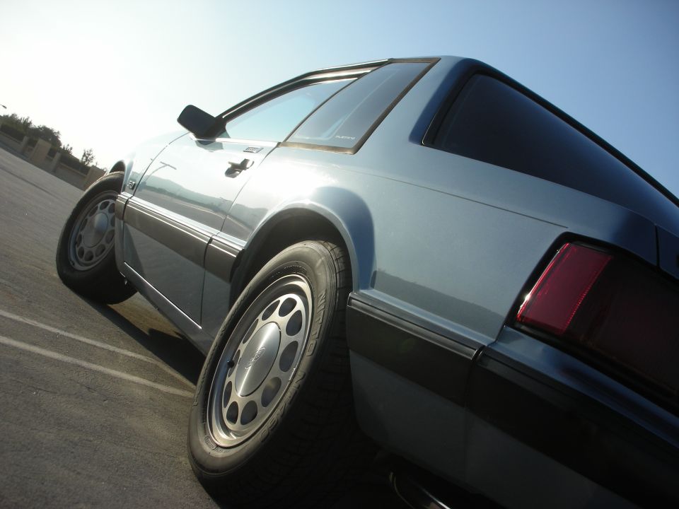 Light blue 1990 Ford Mustang coupe, rear quarter view, parked outdoors