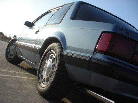 1990 Ford Mustang - A light blue coupe is parked outdoors under a clear sky, showing its rear wheel and taillight.