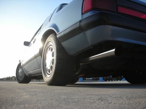1990 Ford Mustang - The rear quarter panel and exhaust pipe of a 1990 Ford Mustang are visible from a low angle.