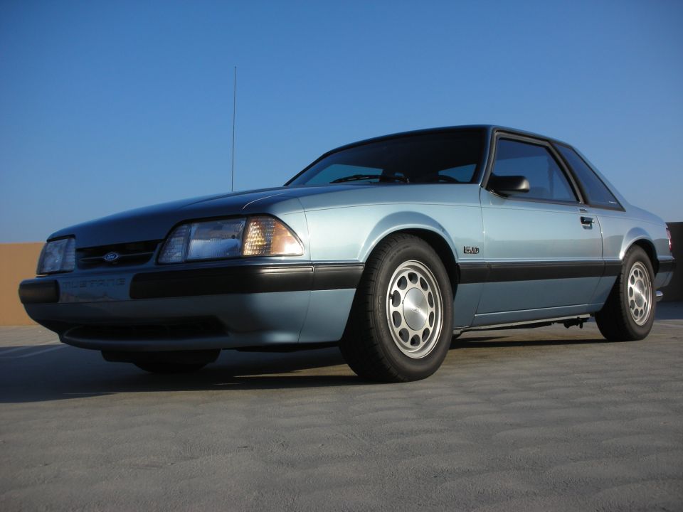 Blue 1990 Ford Mustang coupe, front 3/4 view, parked on concrete